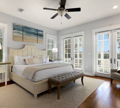Your serene master bedroom features coastal charm with ocean artwork, French doors to your private balcony, and elegant furnishings for restful nights.