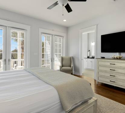 Wake up refreshed in your serene bedroom with plush bedding, modern TV, and French doors opening to peaceful views.