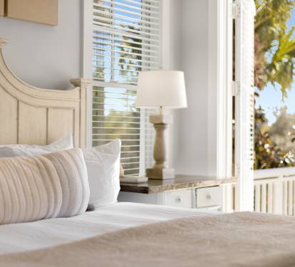 Wake up to tropical views streaming through your private balcony doors, where soft linens and coastal charm create your perfect retreat.