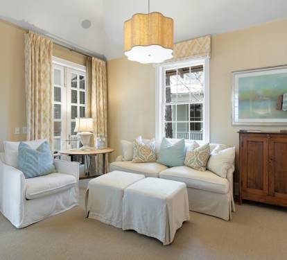 Sink into plush seating in your elegant living room, where soft blue pillows complement cream sofas under warm pendant lighting.
