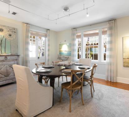 Gather around this elegant oval table where natural light streams through French doors, creating the perfect setting for your memorable meals.