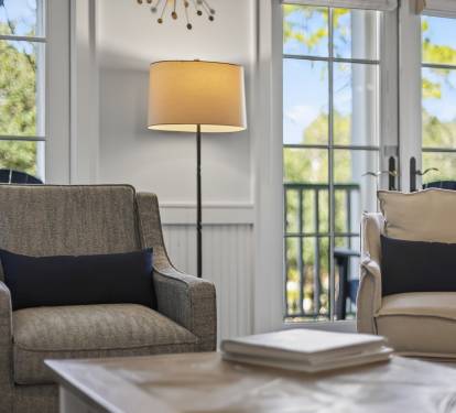 Settle into plush armchairs by sun-filled windows where natural light dances through elegant frames, creating your perfect reading nook.