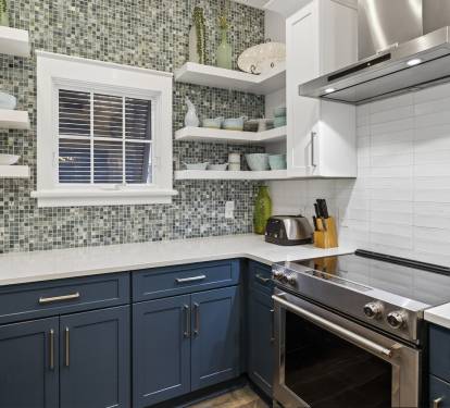 You'll love cooking in this stylish kitchen featuring beautiful mosaic tile backsplash, navy cabinets, and modern stainless steel appliances.