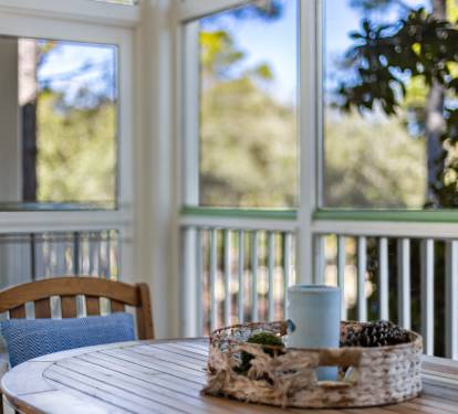 Your bright dining nook overlooks lush greenery through floor-to-ceiling windows, creating a peaceful breakfast spot bathed in natural light.