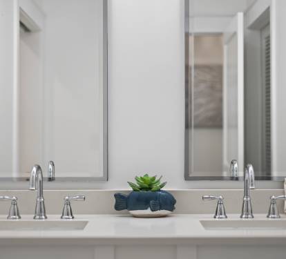 You'll love this elegant dual-sink vanity with soft lighting and thoughtful touches like fresh greenery to start your mornings right.