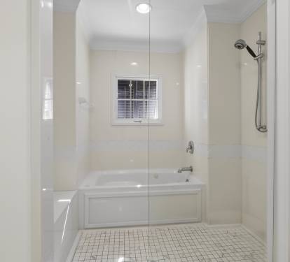 Your spacious bathroom features a luxurious soaking tub and walk-in shower with gleaming white marble surrounds.
