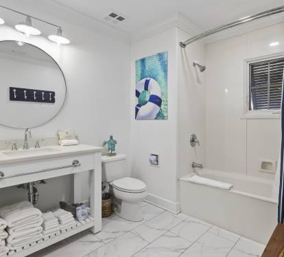 Unwind in this bright, modern bathroom featuring a soaking tub and coastal-themed touches that make your stay feel serene.