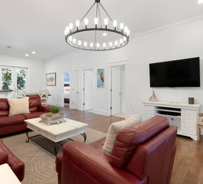Sink into plush leather seating beneath an elegant chandelier in your spacious living area, perfect for cozy movie nights.