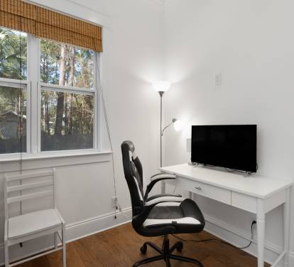 Your bright workspace features a sleek desk, comfortable chair, and TV - perfect for remote work with peaceful garden views.