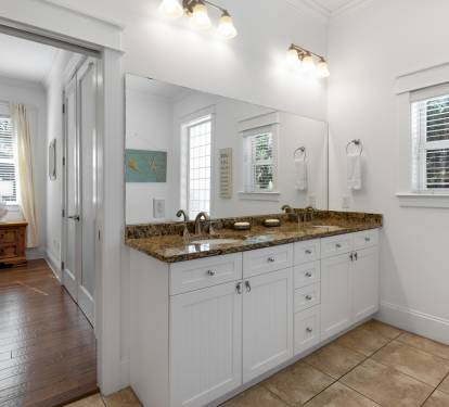 Refresh in your spacious bathroom featuring dual sinks, granite counters, and bright natural light from large windows.