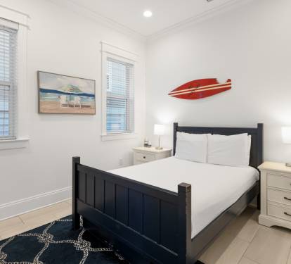 Rest easy in your coastal bedroom with crisp white linens and cheerful surf-themed decor that captures beachside charm.