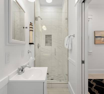 Step into your pristine bathroom with marble shower, fresh towels, and coastal artwork creating a spa-like retreat.