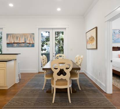 Gather around this elegant dining table where meaningful conversations flow as easily as your morning coffee, with natural light streaming through French doors.