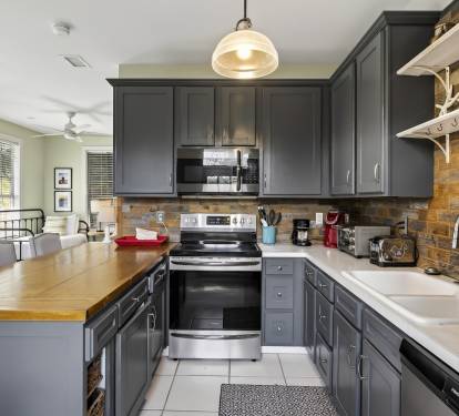 Your fully equipped kitchen features sleek gray cabinets, rustic wood backsplash, and modern stainless appliances for memorable meal prep.