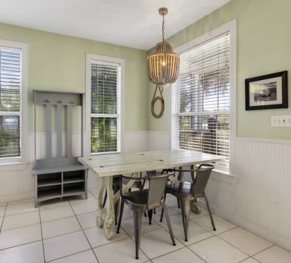 Gather around your bright dining nook with farmhouse charm, featuring a rustic table surrounded by windows that fill the space with natural light.