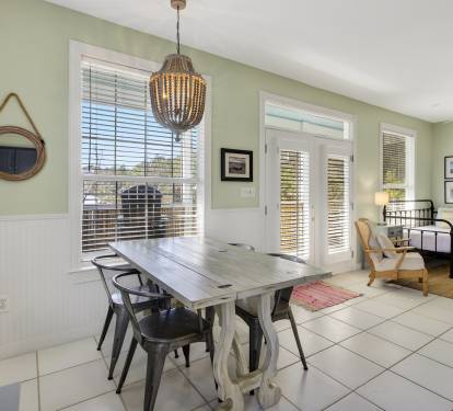 Gather around this rustic dining table where memories are made, with natural light streaming through French doors.