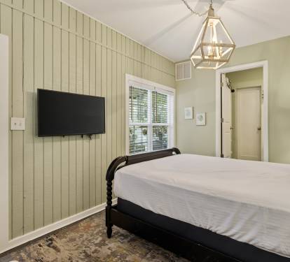 Settle into this charming bedroom with crisp linens, soothing green walls, and modern amenities for your perfect night's rest.