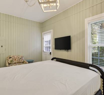 Sink into crisp white linens in your charming bedroom, where soft green walls and natural light create the perfect retreat.