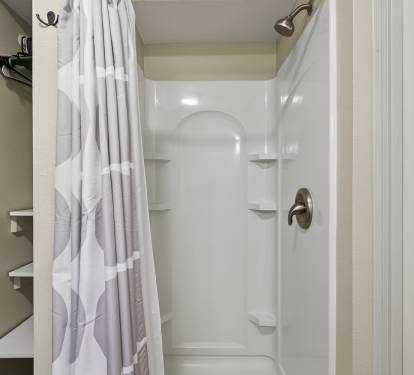 Step into your private shower sanctuary with fresh white linens, convenient corner shelves, and everything ready for your refreshing morning routine.