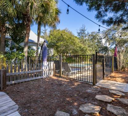 Private backyard oasis with pool access, palm trees, and cozy string lights for evening relaxation.