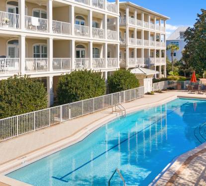 Elegant multi-story vacation property featuring a pristine swimming pool surrounded by lush landscaping and stylish balconies.