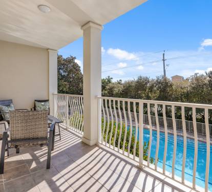 Relax on your private balcony with wicker seating while enjoying stunning pool views and lush surroundings.