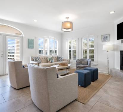 Relax in your bright living room with cozy fireplace, comfortable seating, and peaceful shuttered windows creating the perfect retreat.