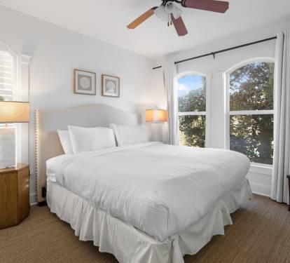 You'll love waking up in this serene bedroom with crisp white linens and warm natural light flooding through beautiful arched windows.