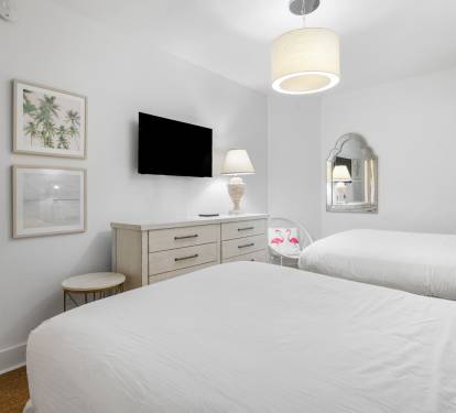 Sink into crisp white linens in your bright, tropical-themed bedroom with modern TV and thoughtful coastal touches for restful nights.