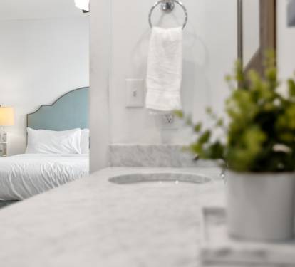 Unwind in your serene bedroom sanctuary where marble textures meet soft linens and fresh greenery creates a peaceful retreat.