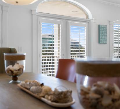Relax in your bright dining space with elegant arched windows and plantation shutters filtering natural light beautifully.