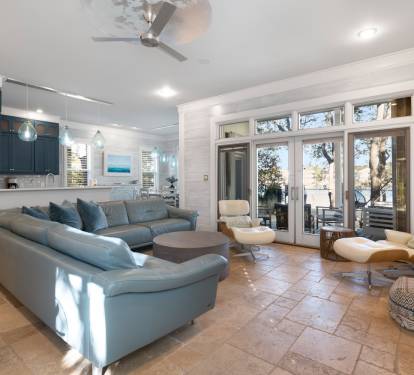 Sink into plush blue sectional seating while natural light streams through French doors, creating your perfect reading nook with built-in bookshelves nearby.