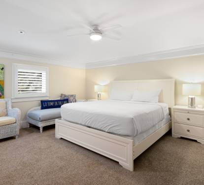 Sink into your cozy bedroom's plush white bedding and enjoy the ceiling fan's gentle breeze after exploring the colorful local art adorning the walls.