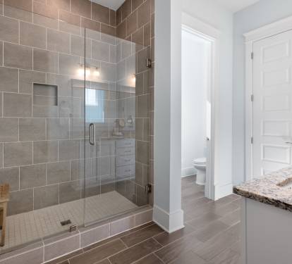 Step into your spa-like sanctuary with a gorgeous walk-in shower featuring elegant gray tiles and warm lighting for ultimate relaxation.