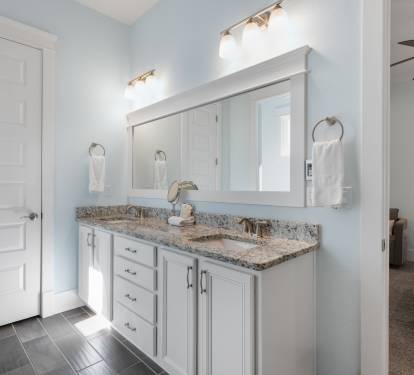 Your elegant bathroom features double vanities with granite countertops and soft blue walls for a serene morning routine.