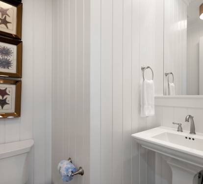 Step into your private coastal-themed bathroom with charming beadboard walls and nautical artwork that captures seaside serenity.