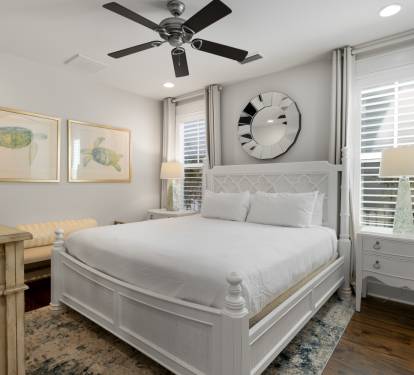 Rest peacefully in this elegant bedroom featuring a plush queen bed, calming sea turtle artwork, and gentle ceiling fan for your comfort.