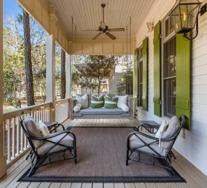Unwind on your private covered porch with plush seating and swing bed, surrounded by mature trees for peaceful relaxation.