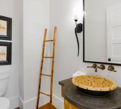Step into your stylishly designed powder room featuring a striking woven vessel sink and warm brass fixtures that create an inviting, spa-like atmosphere.