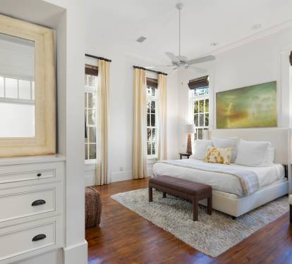 Unwind in your serene bedroom sanctuary with crisp white linens, warm wood floors, and natural light streaming through elegant windows.
