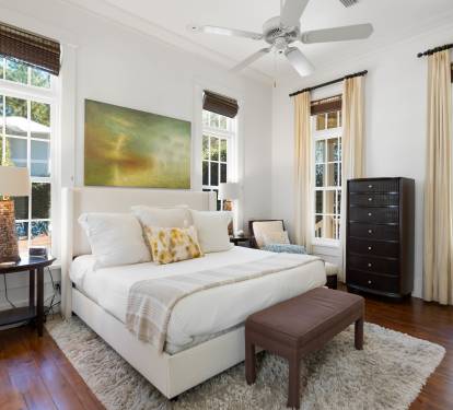 Unwind in your serene master bedroom with crisp linens, original hardwood floors, and peaceful garden views through charming French doors.