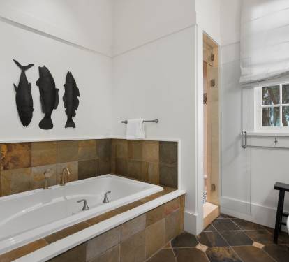 Unwind in your spa-like bathroom with a deep soaking tub surrounded by elegant stone tiles and artistic fish silhouettes.