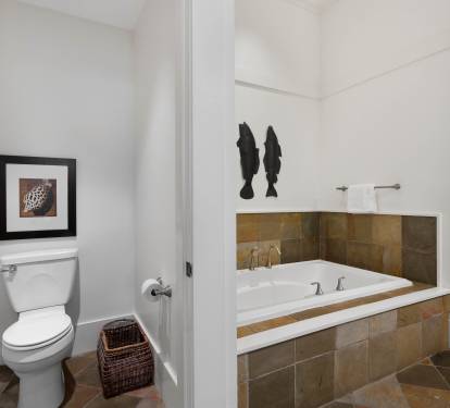 Unwind in your private spa-like bathroom with a deep soaking tub surrounded by warm stone tiles and elegant fixtures.