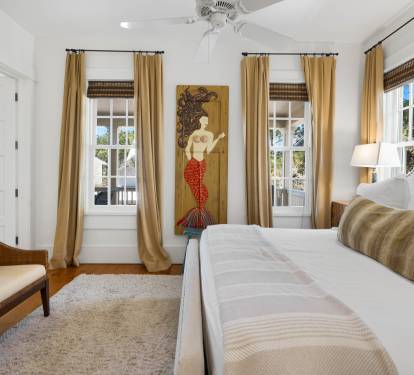 Relax in your elegantly appointed bedroom featuring a plush king bed, cozy seating area, and cheerful windows that flood the space with natural light.