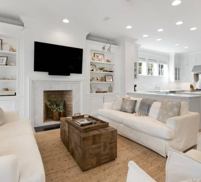 Sink into plush white sofas by the fireplace while your favorite shows play on the wall-mounted TV in this bright, open living space.