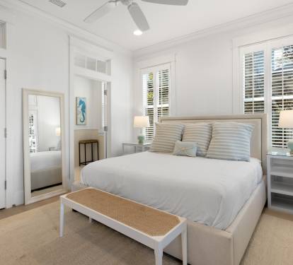 Drift off to peaceful sleep in this bright, airy bedroom where coastal charm meets comfort beneath gentle ceiling fans.