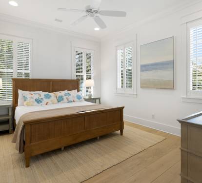 Your bright bedroom features coastal charm with crisp white linens, elegant wood furnishings, and plantation shutters filtering gentle natural light.