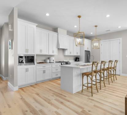 You'll love cooking in this bright, modern kitchen featuring pristine white cabinets, elegant brass pendant lights, and a spacious island perfect for gathering.