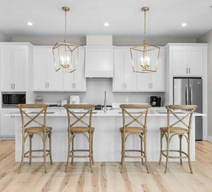 Your bright kitchen awaits with gleaming white cabinets, marble countertops, and cozy breakfast bar seating for four.