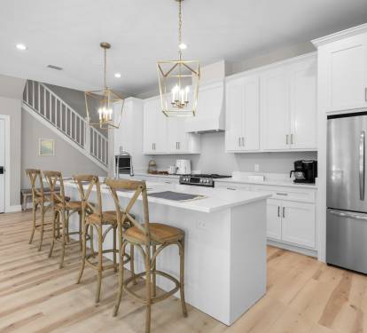 Step into your bright, modern kitchen where gleaming white cabinets and elegant pendant lighting create the perfect space for morning coffee and memorable meals together.